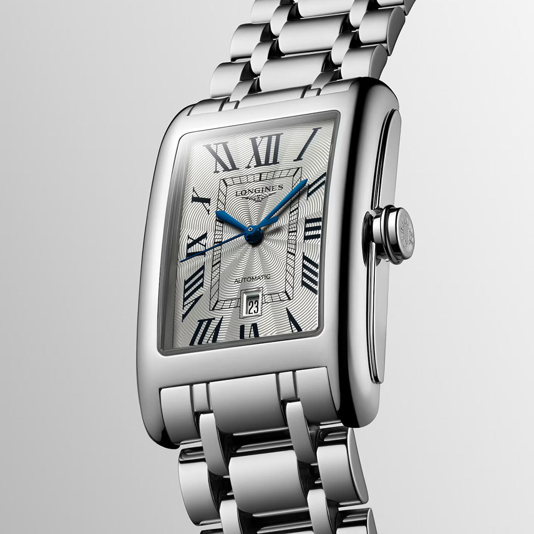 The Longines Dolcevita Automatic 28.2 x 47mm Watch, featuring a silver square face with Roman numerals, blue hands, a date window, and a metal link bracelet, is displayed on a light gray background—an exquisite choice from Longines for those who value elegant timepieces.