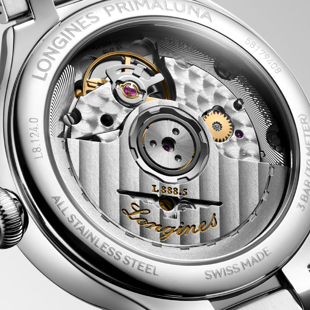 A close-up of the Longines Primaluna Automatic 34mm Watch displays its elegant automatic movement through a transparent case back, engraved with “Longines,” “Swiss Made,” and “All Stainless Steel.”.