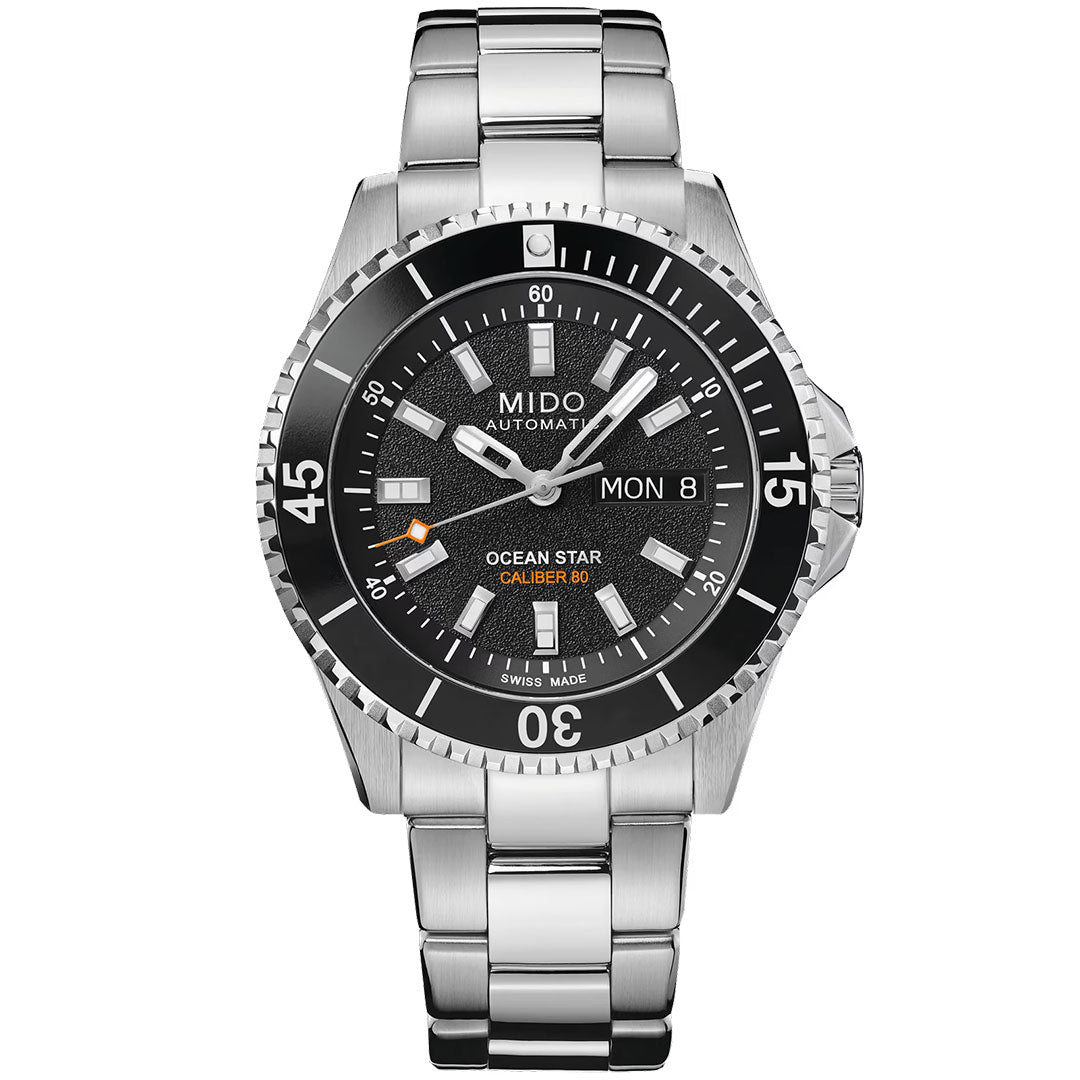 The MIDO Ocean Star GMT Automatic 44mm Watch features a stainless steel case, black dial, silver markers, day-date display, orange accents, and a metal link bracelet.