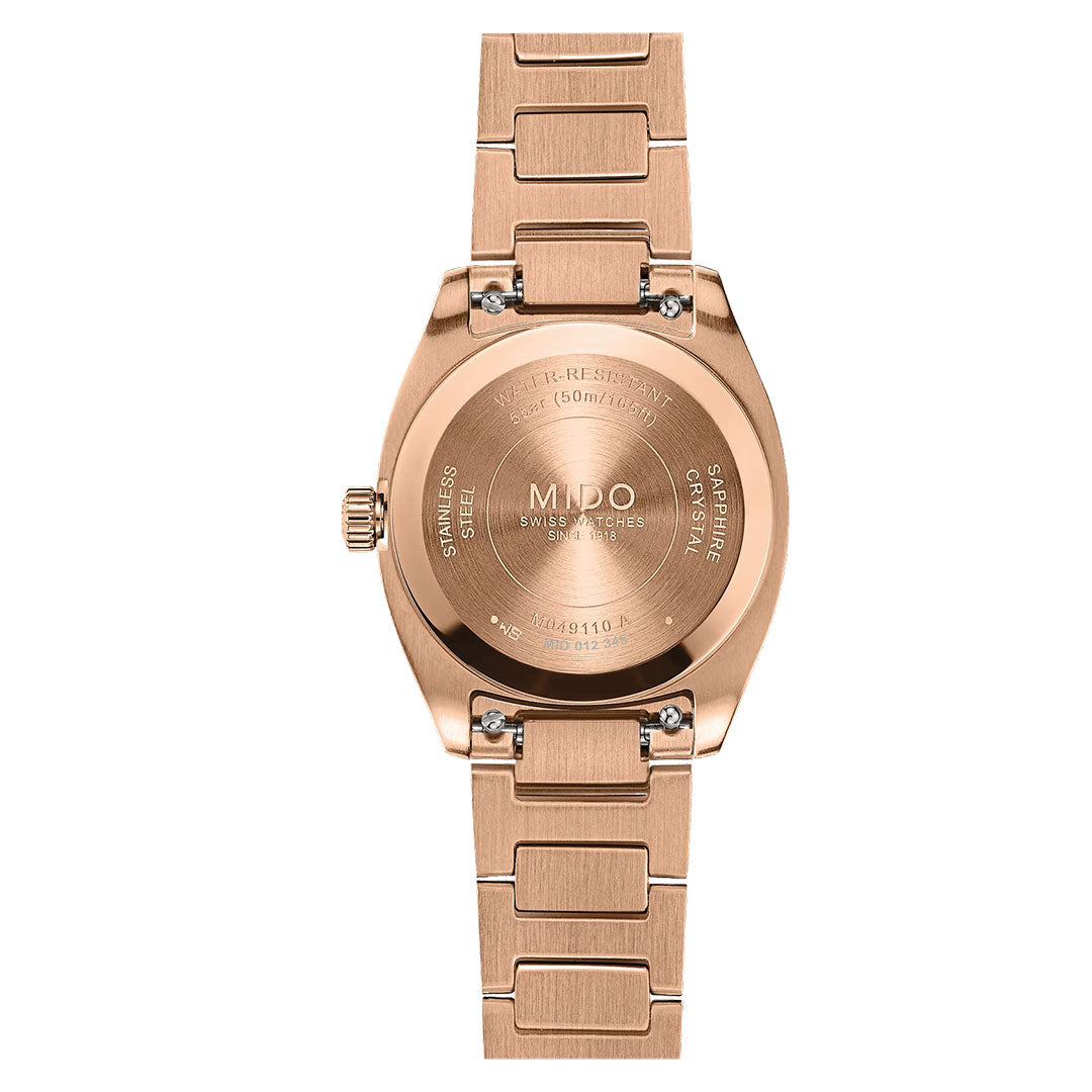 A rose gold MIDO Multifort TV Quartz 28mm watch is pictured from the back, revealing engraved details about the MIDO brand, water resistance, sapphire crystal, stainless steel construction, and serial number.