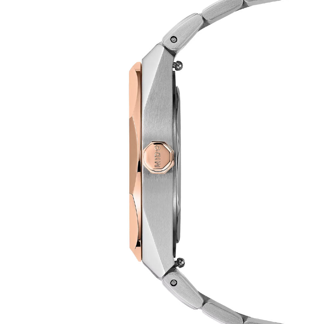 Side view of the MIDO Multifort 8 One Crown Automatic 40mm Watch: a silver wristwatch with rose gold bezel and hexagonal crown, metal link band, and slim profile. The Swiss automatic movement ensures precision. Brand: MIDO.
