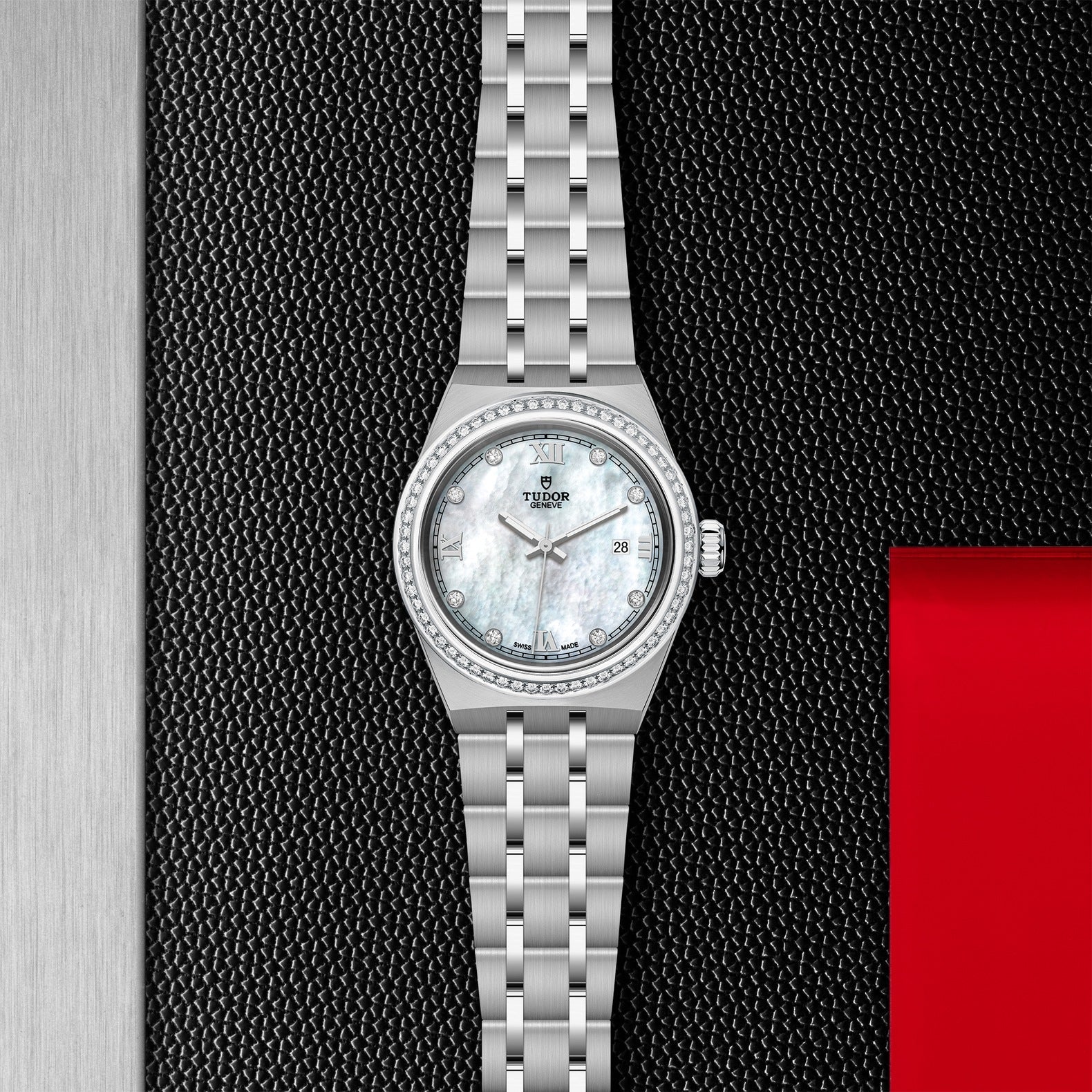 Positioned against a textured black background with a red accent, the TUDOR Royal exhibits sport-chic elegance. This stainless steel wristwatch boasts a mother-of-pearl face adorned with diamond hour markers and comes with a metal link bracelet. It also features an automatic date window situated at the 3 o'clock position.