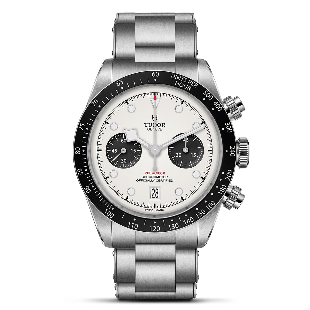 The TUDOR Black Bay Chrono is a stainless steel watch with a silver bracelet and T-Fit clasp. It has a round white dial with two black subdials, a date display at 6 o'clock, and a tachymetric bezel. The brand name, TUDOR, appears below the 12 o'clock marker.
