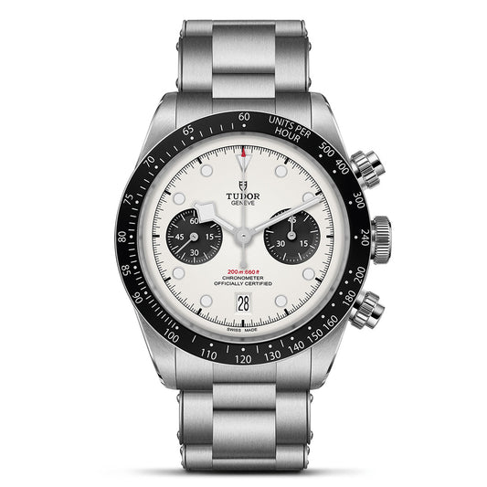 The TUDOR Black Bay Chrono is a stainless steel watch with a silver bracelet and T-Fit clasp. It has a round white dial with two black subdials, a date display at 6 o'clock, and a tachymetric bezel. The brand name, TUDOR, appears below the 12 o'clock marker.