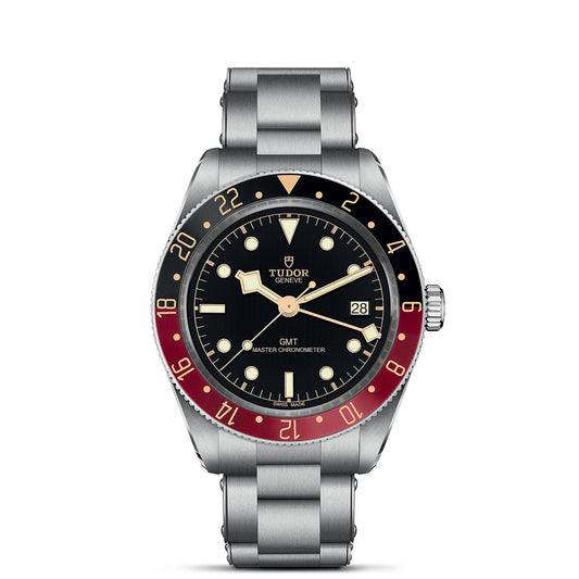 The TUDOR Black Bay 58 GMT wristwatch showcases a silver metal band, a black dial, and a striking red and black bezel. This dive watch from TUDOR includes luminous hour markers, a date window, and prominently displays the "GMT Master Chronometer" label on its face.