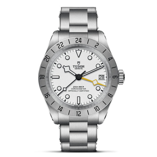 The TUDOR Black Bay Pro is a stainless steel wristwatch with a white dial, luminous black hour markers and hands, a date display at 3 o'clock, and "Tudor" below 12 o'clock. It features a dual time zone bezel with a 24-hour scale and houses the TUDOR Manufacture Calibre MT5652.