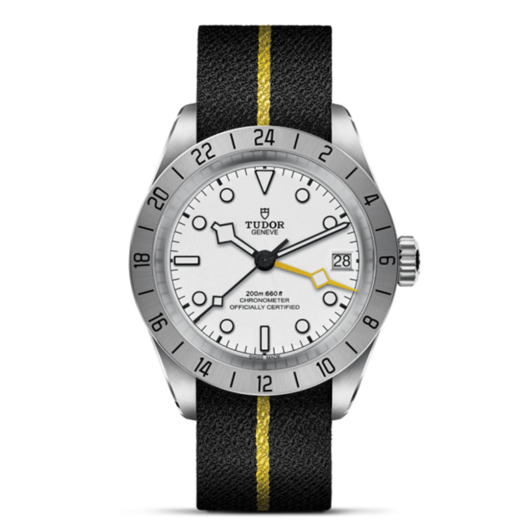 The TUDOR Black Bay Pro by TUDOR is a stainless steel watch with a white face, black and yellow striped strap, and numbered bezel. It offers dual time zone functionality, a date indicator at 3 o'clock, and a yellow-tipped second hand. It's powered by the TUDOR Manufacture Calibre MT5652.