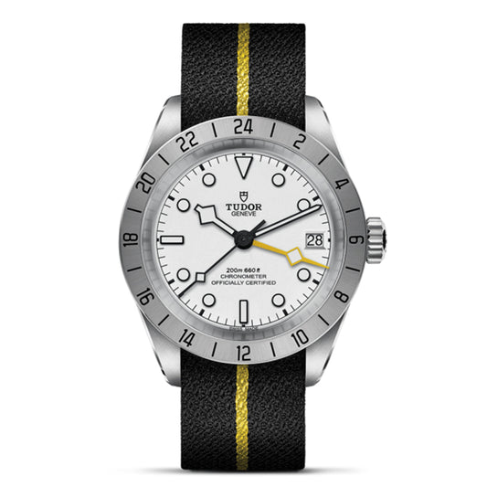 The TUDOR Black Bay Pro by TUDOR is a stainless steel watch with a white face, black and yellow striped strap, and numbered bezel. It offers dual time zone functionality, a date indicator at 3 o'clock, and a yellow-tipped second hand. It's powered by the TUDOR Manufacture Calibre MT5652.
