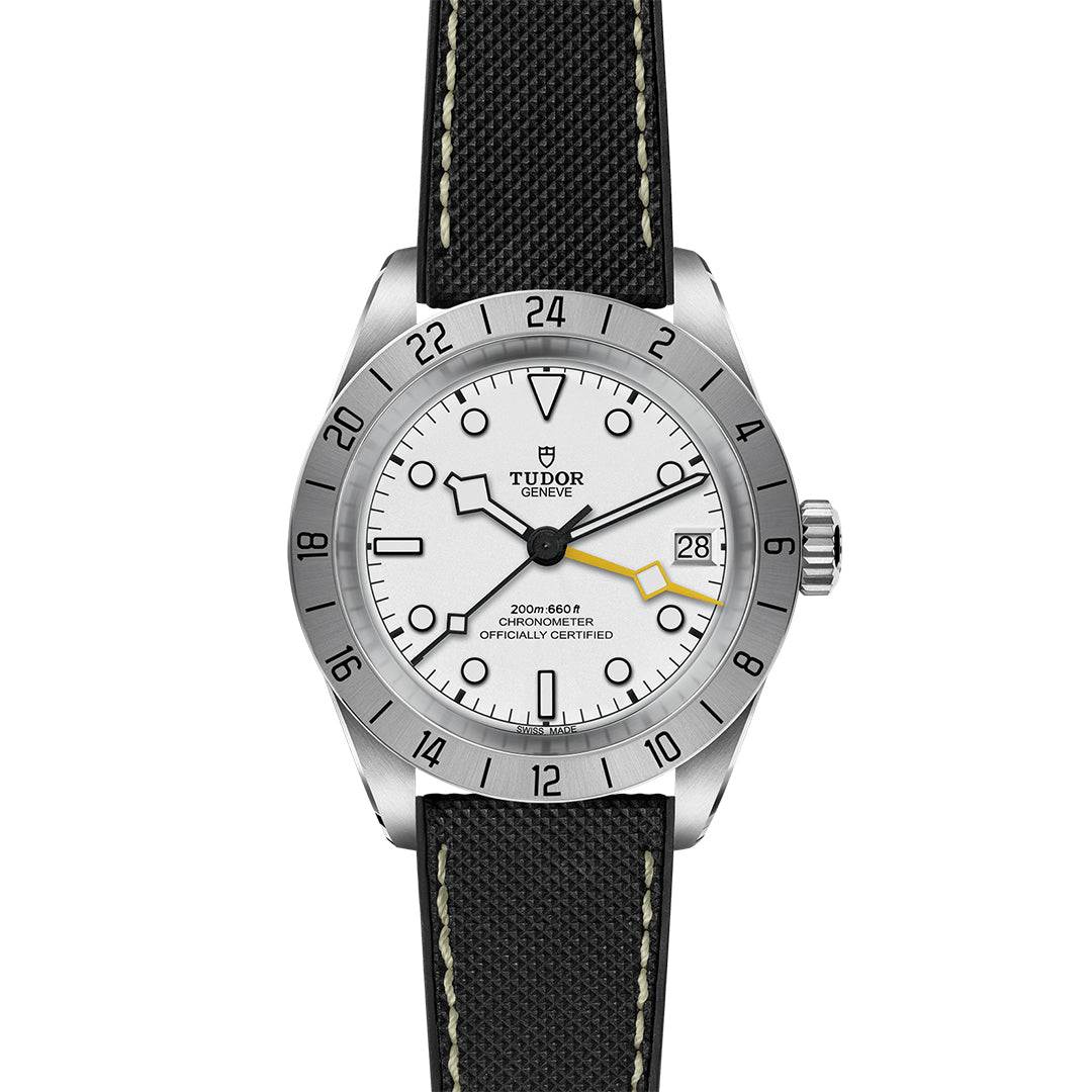 The TUDOR Black Bay Pro combines a white dial with black Arabic numerals and the precision of the TUDOR Manufacture Calibre MT5652. Its silver bezel features engraved numerals, while a black strap with white stitching enhances elegance. Black outlined hands and a yellow seconds hand offer dual time zone functionality.