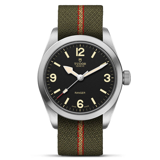 The TUDOR Ranger by TUDOR features a black dial with cream numerals at 12, 3, 6, and 9, luminous hands, Manufacture Calibre MT5400, a stainless steel case, and a green fabric strap with red center stripe for an expedition style.