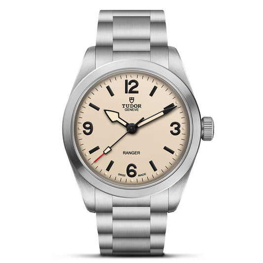 The TUDOR Ranger by TUDOR is a stainless steel wristwatch with a cream dial, black hour markers, numerals at 12/3/6/9 o’clock, simple black hands with a red-tipped seconds hand, and a metal bracelet.