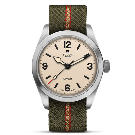 The TUDOR Ranger by TUDOR features a beige dial with bold black numerals and markers, a silver bezel, and an olive green fabric strap with a red stripe. Inspired by expedition watches, it offers excellent legibility.