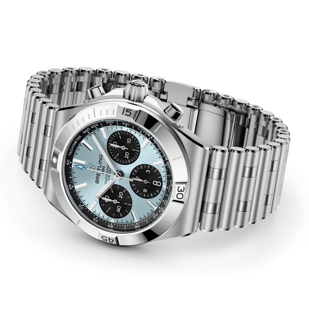 The BREITLING Chronomat B01 Chronograph 42, by Breitling, features a stainless steel case, silver metal band, light blue dial with three black chronograph subdials, and silver hour markers, displayed at an angle on a white background.