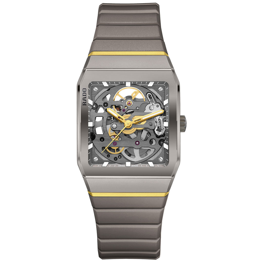 The RADO Anatom Automatic Skeleton 32.5mm Watch features a rectangular silver and gold case, a skeleton dial with visible gears, yellow-accented hands and case, metal strap, and "RADO" branding on the ergonomic left side.