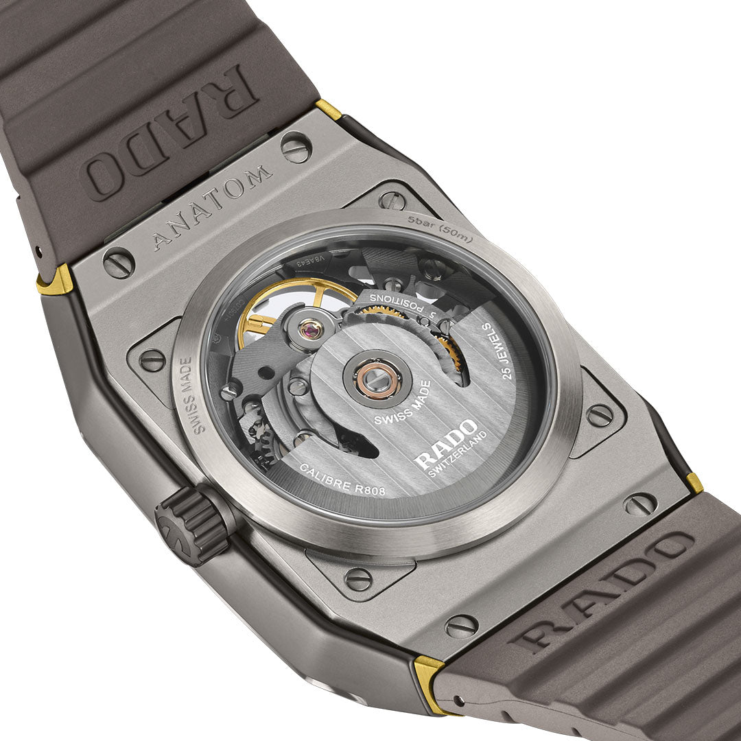 A close-up of the RADO Anatom Automatic Skeleton 32.5mm Watch showcases its transparent case back, displaying the visible automatic movement and "SWISS MADE" and "RADO" engravings on the metal and rubber strap.