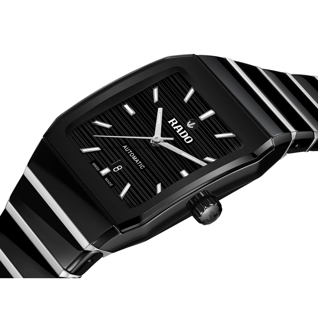 The RADO Anatom Automatic 27.5mm Watch features a refined black design with a rectangular face, silver hour markers, a date window at 6 o’clock, and a black high-tech ceramic strap from RADO, elegantly displayed at an angle against a white background.