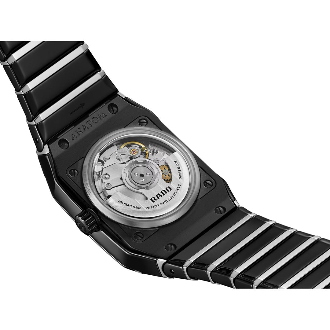 Close-up of the back of the RADO Anatom Automatic 27.5mm Watch in black, showcasing its exposed movement through a transparent case back with visible metal gears and text details. The refined design highlights RADO’s signature high-tech ceramic craftsmanship.