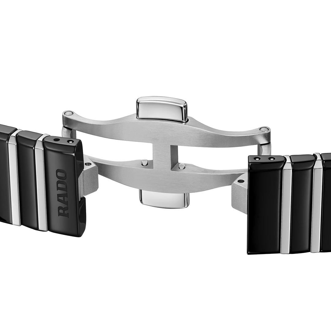 Close-up of the RADO Anatom Automatic 27.5mm watch clasp, showcasing a stainless steel deployment buckle flanked by black high-tech ceramic bracelet links. The RADO logo appears on the left link.