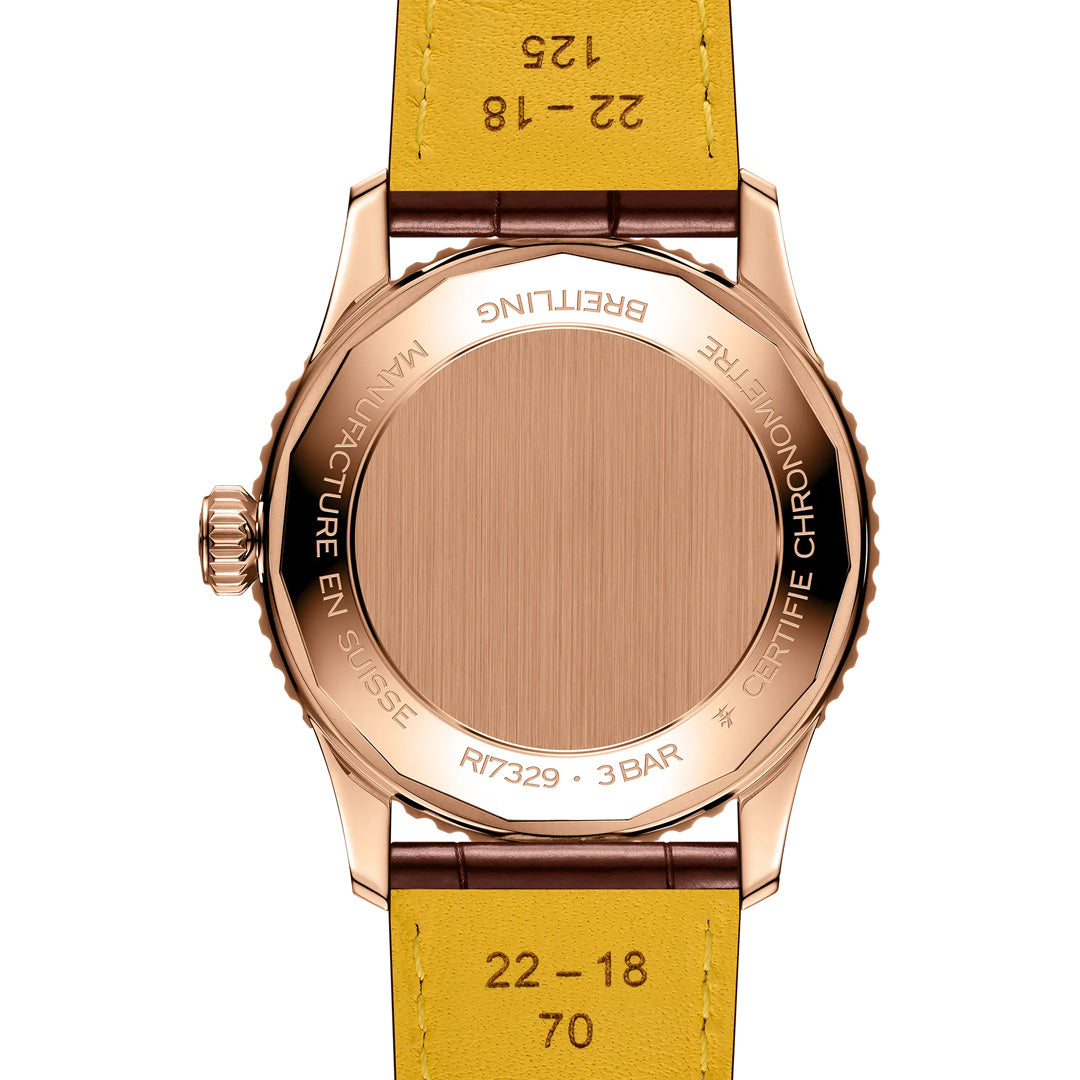 Close-up of the back of a BREITLING Navitimer Automatic 41 wristwatch by Breitling, featuring a gold case and yellow leather strap. The watch back displays engraved text and has a fluted crown on the left side, highlighting its automatic GMT capability.