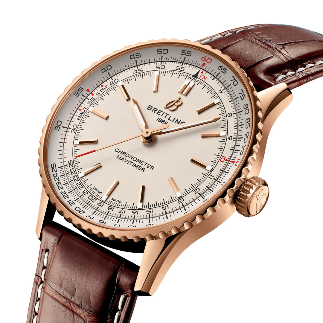 A close-up of the BREITLING Navitimer Automatic 41 wristwatch with a rose gold case, white dial, brown leather strap, and detailed chronometer markings highlights the elegance and precision of this iconic Breitling timepiece.