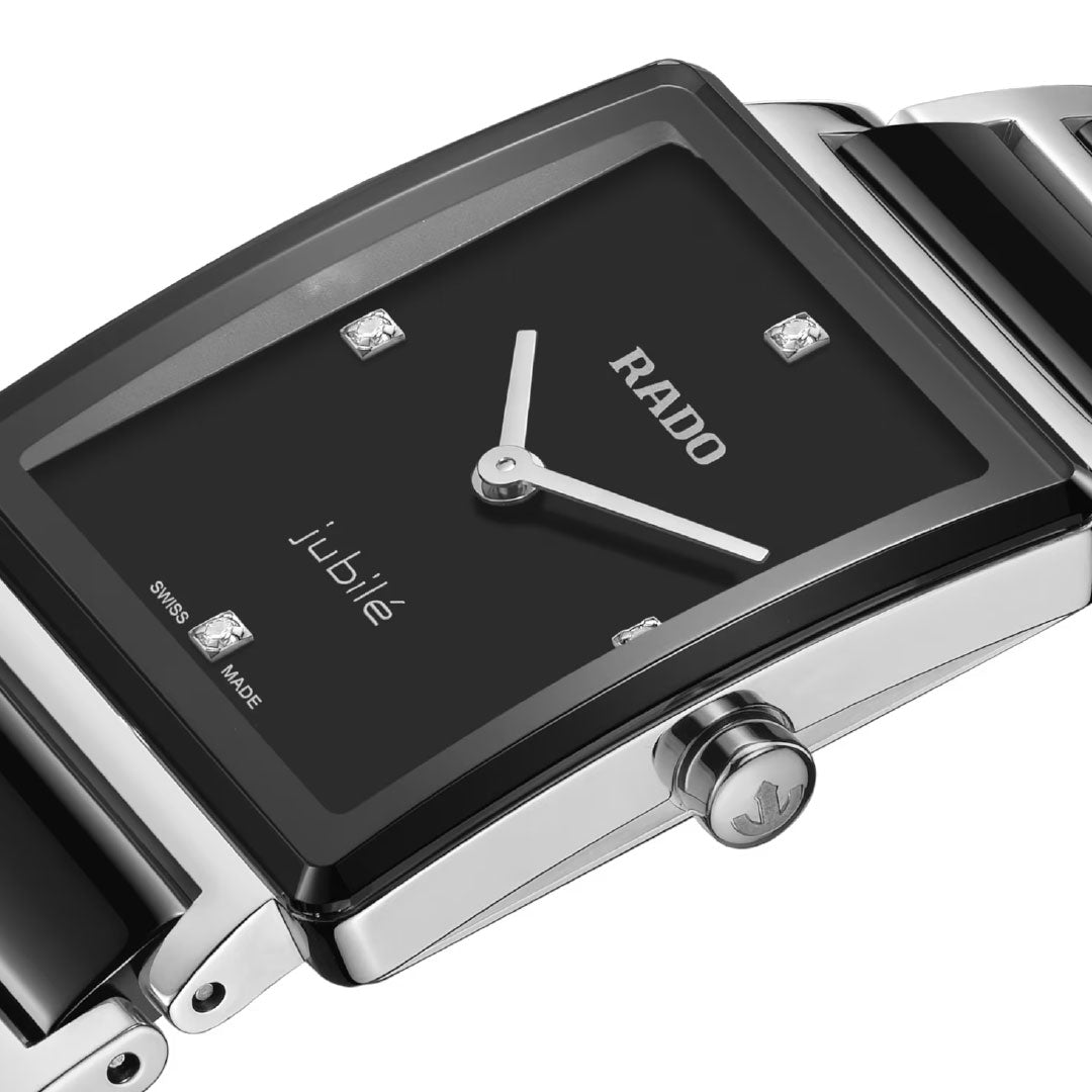 A close-up of the RADO Integral Diamonds Quartz 23mm Watch featuring a black square dial, silver hands, diamond hour markers, and a silver and black bracelet. The high-tech ceramic watch displays "RADO" and "jubile" on the face.