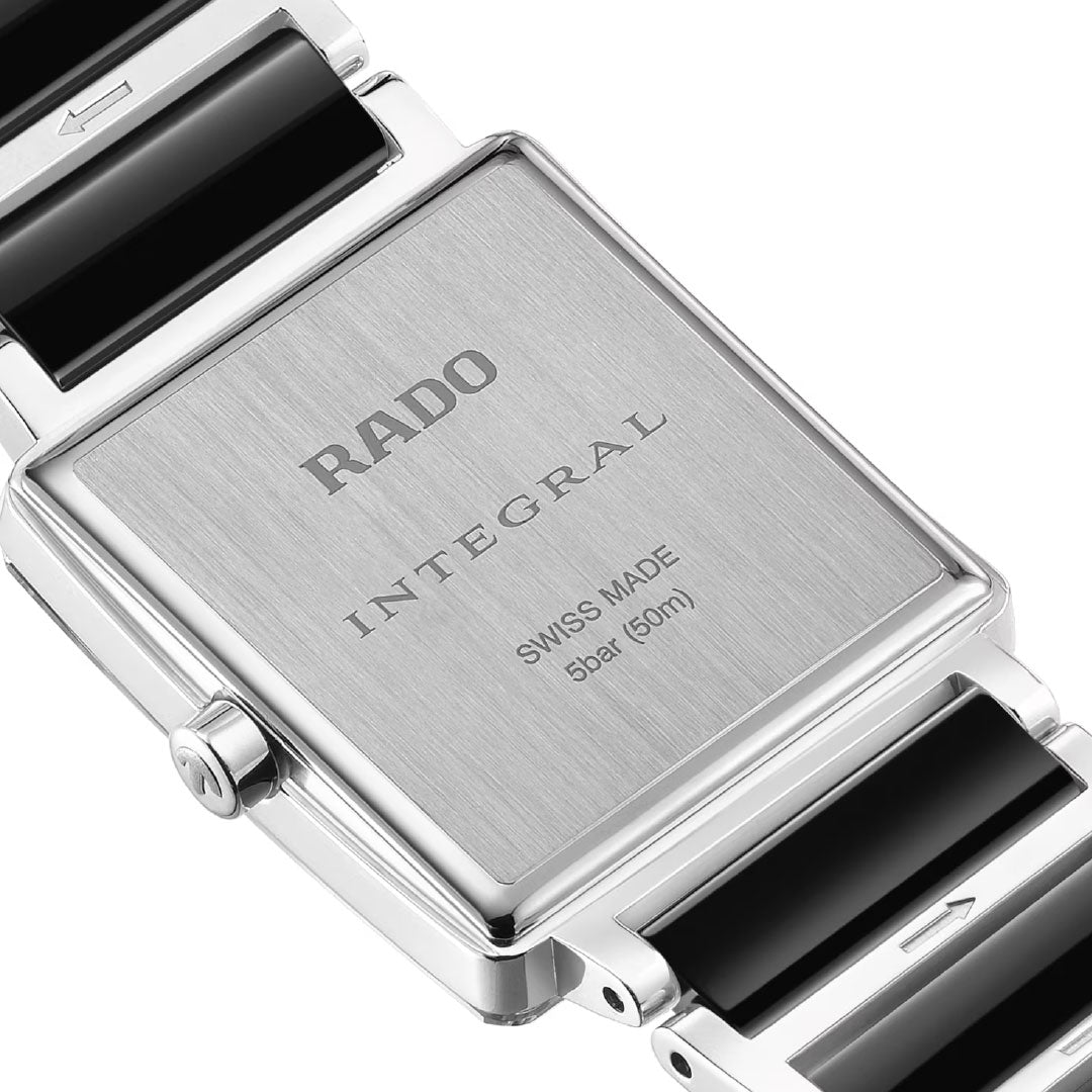 Close-up of the back of a RADO Integral Diamonds Quartz 23mm watch, featuring a brushed metal case engraved with "RADO INTEGRAL SWISS MADE 5bar (50m)", and a black and silver link bracelet.