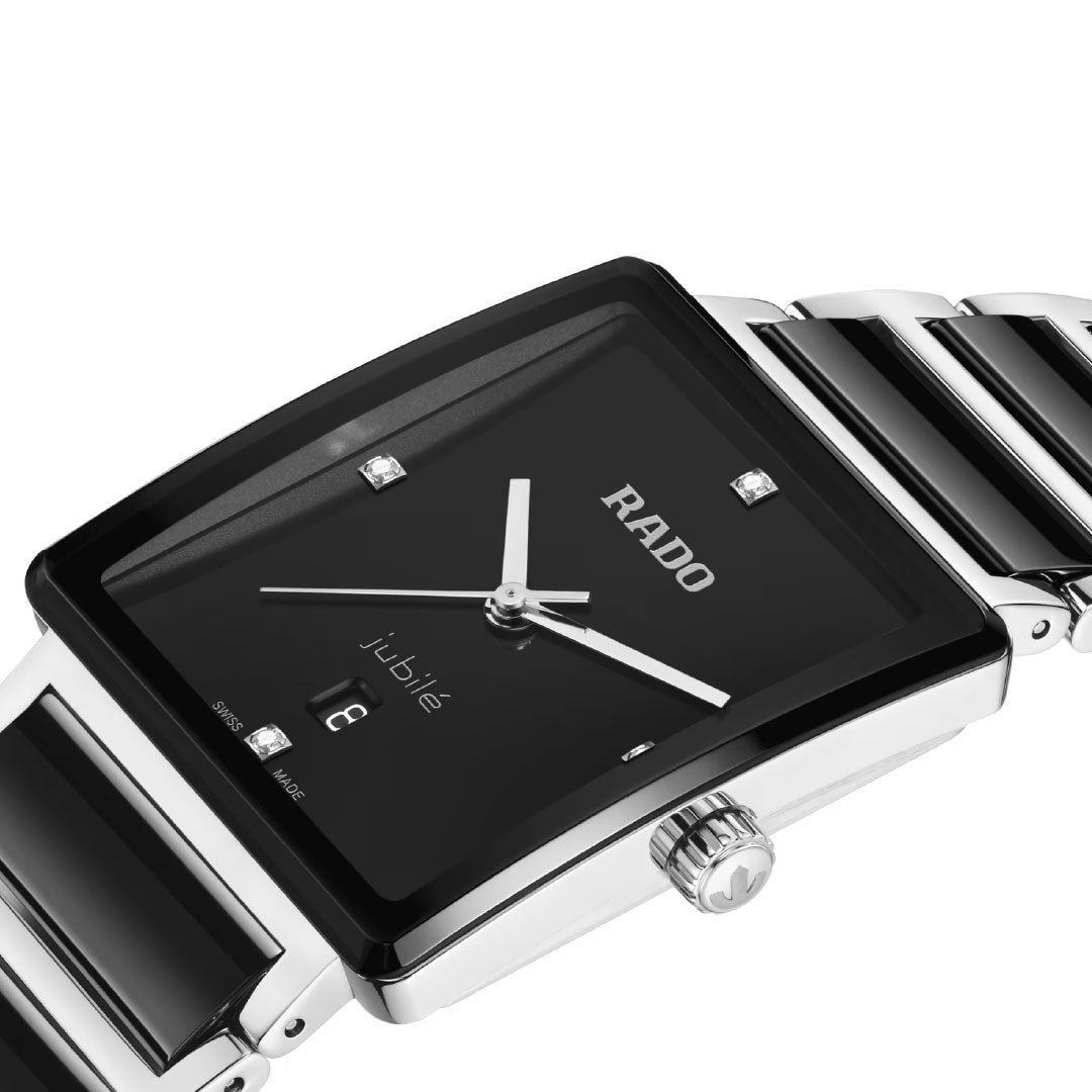 A close-up of the RADO Integral Diamonds Quartz 31.5mm Watch, featuring a rectangular black dial with diamond hour markers, silver-tone hands, date display, and a sleek black and silver stainless steel bracelet.