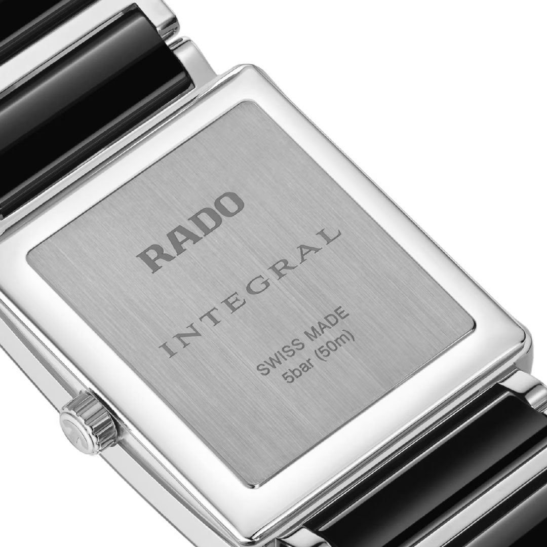 Close-up of the back of a RADO Integral Diamonds Quartz 31.5mm Watch, featuring an engraved plate reading "RADO INTEGRAL SWISS MADE 5 bar (50m)" on a rectangular stainless steel and black ceramic strap.