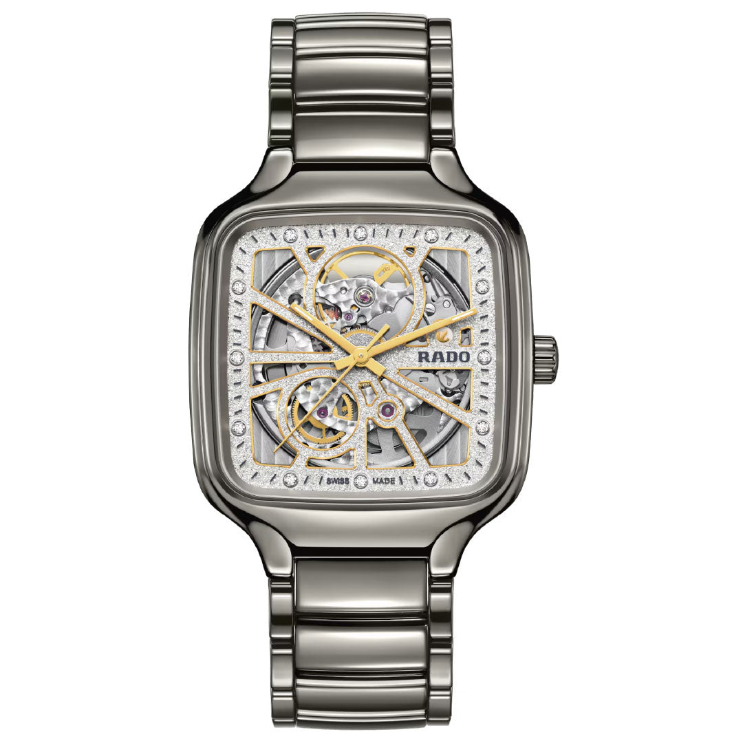 The RADO True Square Automatic Open Heart Sparkling 38mm Watch features a square face, exposed gold and silver mechanics, a diamond dial, and a sleek metal link band.