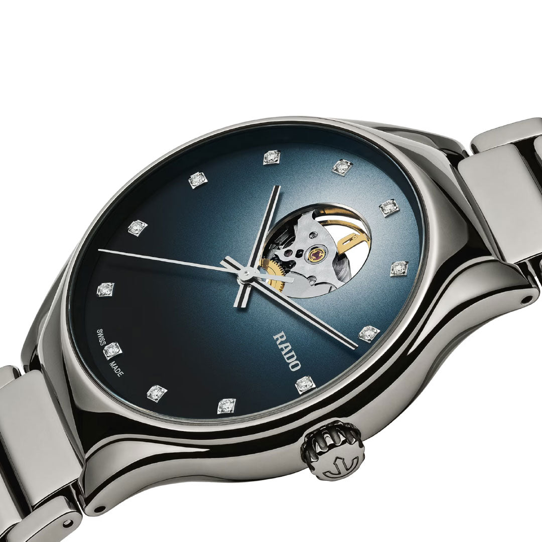 A close-up of the RADO True Round Secret Diamonds Automatic 40mm shows its metallic strap, blue gradient dial with diamond markers, and an exposed Swiss-made automatic movement at 12 o’clock.