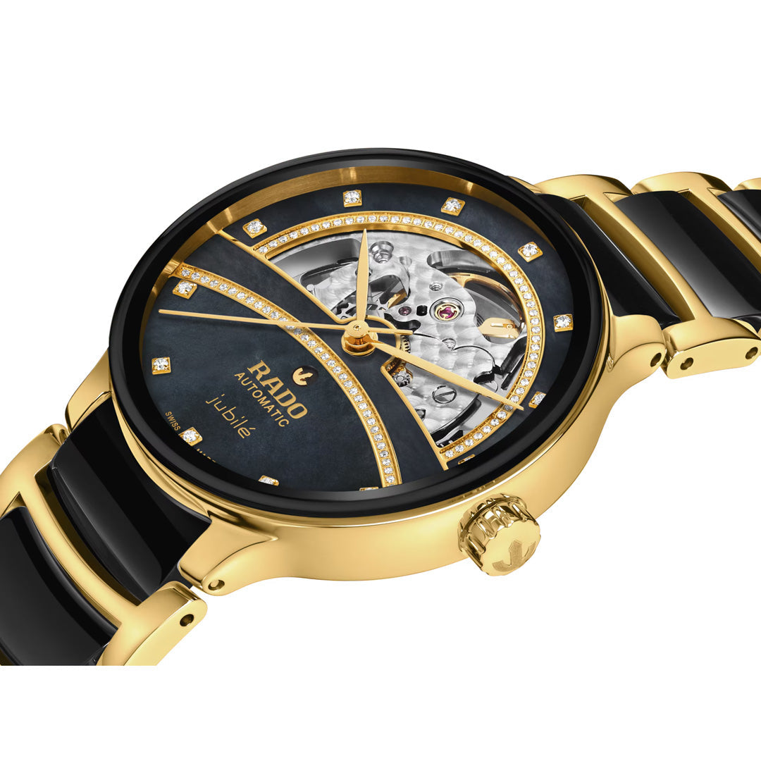 The RADO Centrix Open Heart Automatic 35mm Watch is an exquisite gold and black timepiece featuring a visible skeleton dial, diamond accents, and a ceramic link bracelet; this RADO automatic watch combines precise timekeeping with luxurious design.