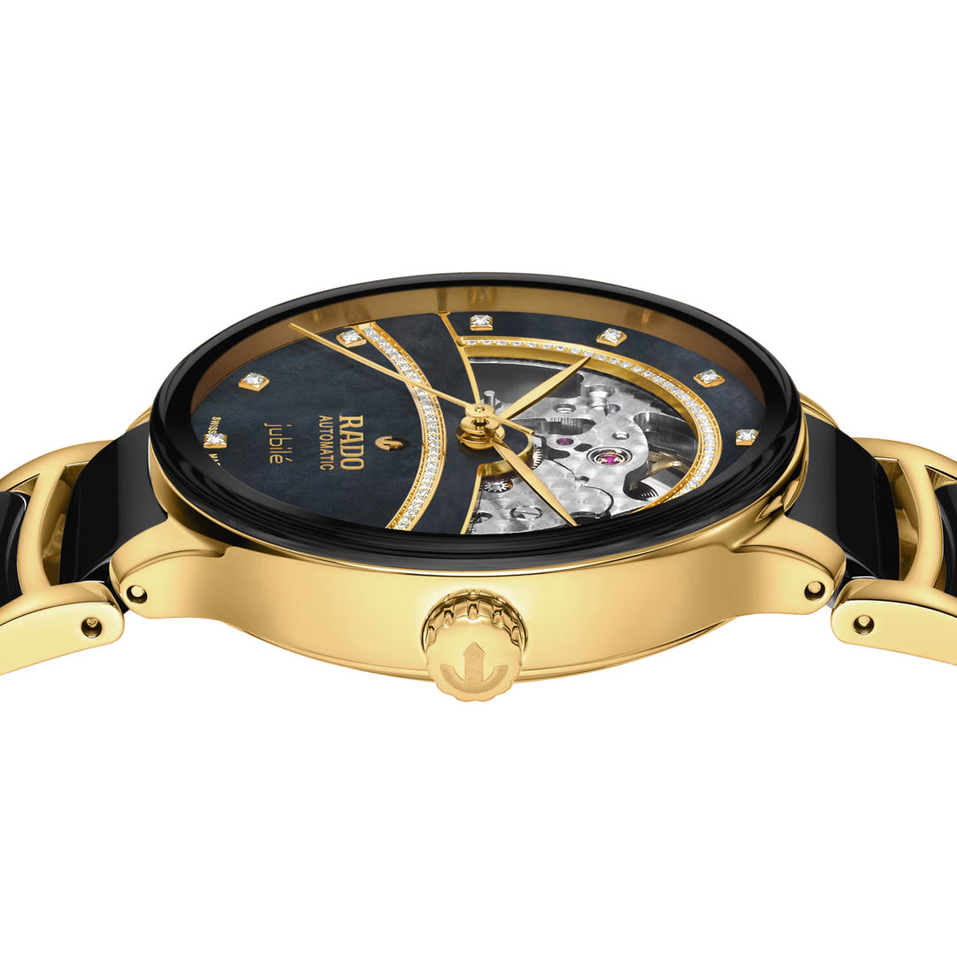 The RADO Centrix Open Heart Automatic 35mm Watch by RADO features a gold finish with a black mother-of-pearl dial, diamond hour markers, exposed mechanical movement, and decorative detailing. The polished crown and case are complemented by gold and black accents on the bracelet.