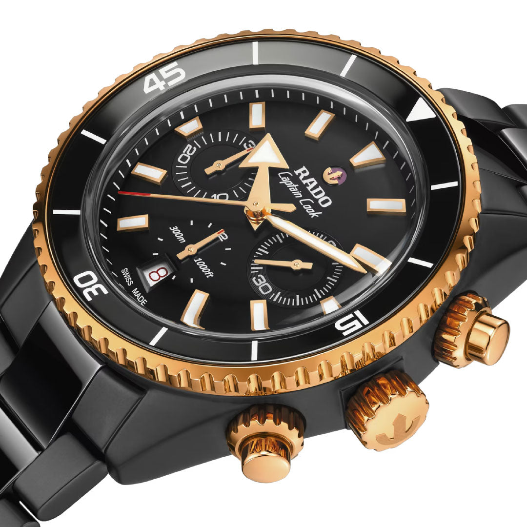Close-up of the RADO Captain Cook High-Tech Ceramic Automatic Chronograph 43mm Watch with sapphire crystal, black dial, gold bezel, two subdials, date at 6 o’clock, self-winding movement, and gold crown and pushers.