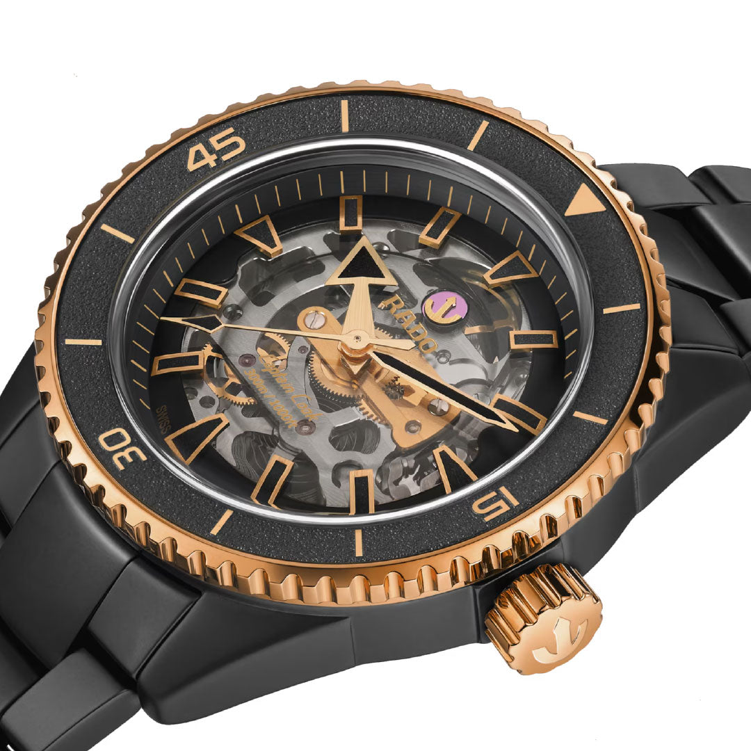 The RADO Captain Cook High-Tech Ceramic Skeleton Automatic 43mm Watch features a black and gold skeleton dial with visible gears, gold hour markers, a black bezel with gold accents, and a sleek black metal link bracelet.
