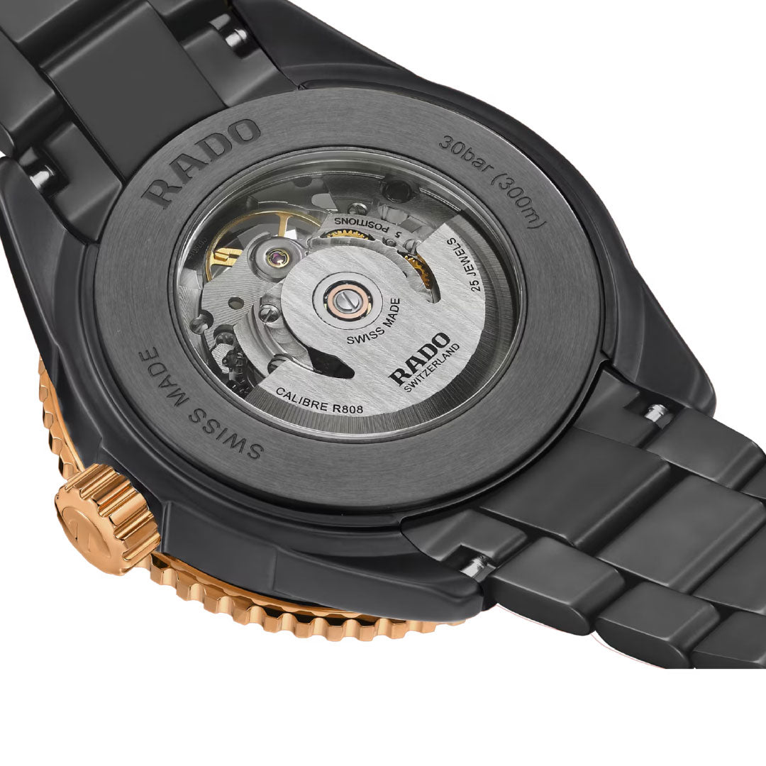 Close-up of the RADO Captain Cook High-Tech Ceramic Skeleton Automatic 43mm Watch, featuring a transparent case back with visible mechanical movement and engraved specs, on a black and gold metal strap.