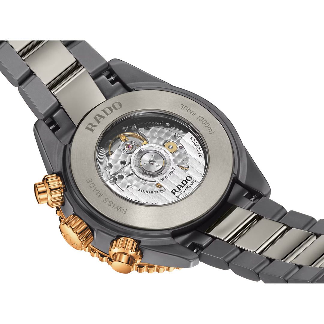Close-up of the back of the RADO Captain Cook Hi-Tech Ceramic Chronograph Automatic 43mm Watch, revealing its automatic movement through a transparent case back. The sophisticated design pairs black and rose gold accents on both the case and bracelet, highlighting RADO’s signature high-tech ceramic chronograph craftsmanship.