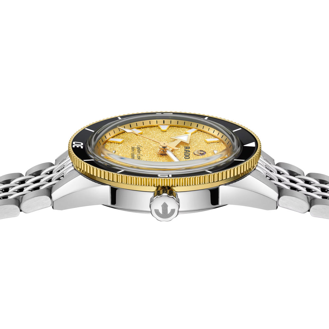 A close-up side view of the RADO Captain Cook Automatic 39mm watch, featuring a silver metal strap, a yellow textured dial, a black-and-gold bezel, and an anchor symbol on the crown—an iconic design inspired by RADO’s classic Captain Cook collection.