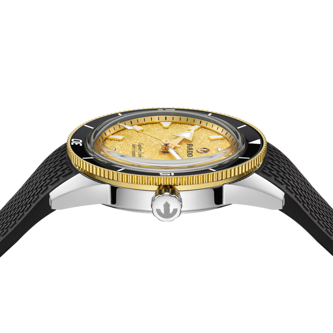 A detailed side-view close-up of the RADO Captain Cook Automatic 39mm Watch highlights its textured gold dial, gold bezel with a black edge, and black strap, prominently displaying the crown and case design.