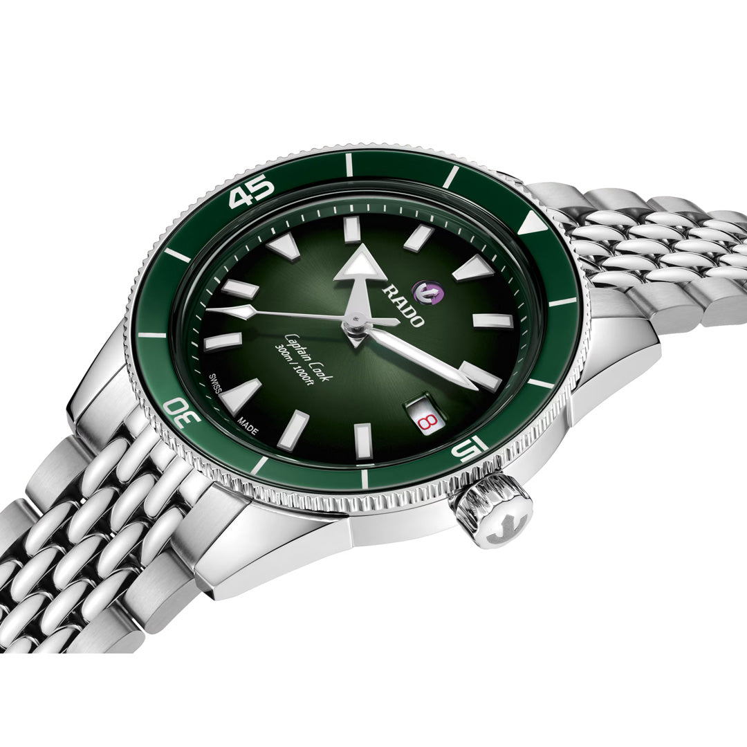 A detailed view of the RADO Captain Cook Automatic 39mm Watch, featuring a green ceramic bezel and dial, silver hour markers, a date display at 3 o’clock, automatic movement, and a metal link bracelet.