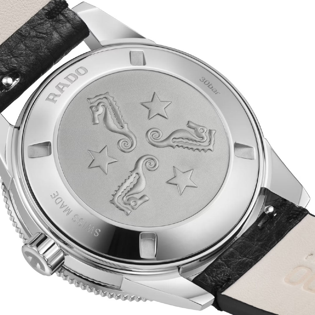 Close-up of the RADO Captain Cook Automatic 39mm Watch’s back, showing engraved seahorses and stars on brushed metal, with a black leather strap and crown—crafted from high-tech ceramic with automatic movement.