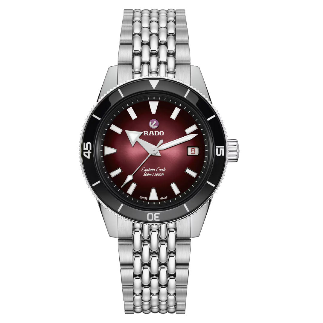 The RADO Captain Cook Automatic 39mm Watch features a silver case with metal link band, gradient red-black dial, silver markers and hands, date window at 3 o’clock, black bezel with white numerals, and precise automatic movement.