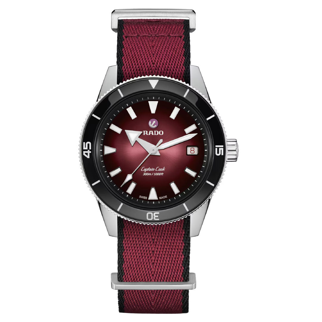 The RADO Captain Cook Automatic 39mm Watch features a burgundy dial, silver hands and markers, date window at 3 o'clock, black bezel, stainless steel case, matching burgundy fabric strap, and automatic movement.