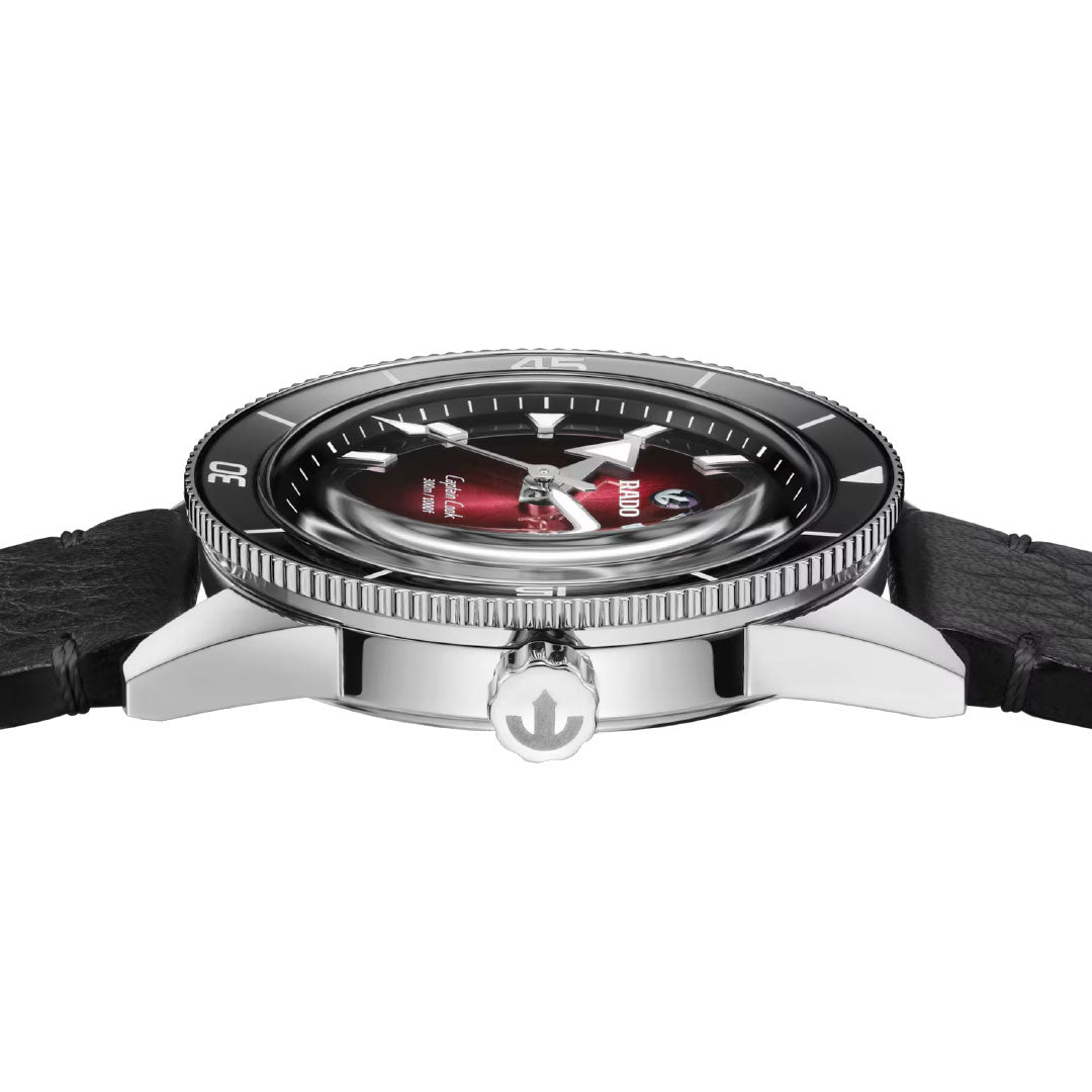 A side view of the RADO Captain Cook Automatic 39mm Watch shows its black leather strap, stainless steel case, black high-tech ceramic bezel, domed crystal over a red and black dial, and an anchor-engraved crown with automatic movement.