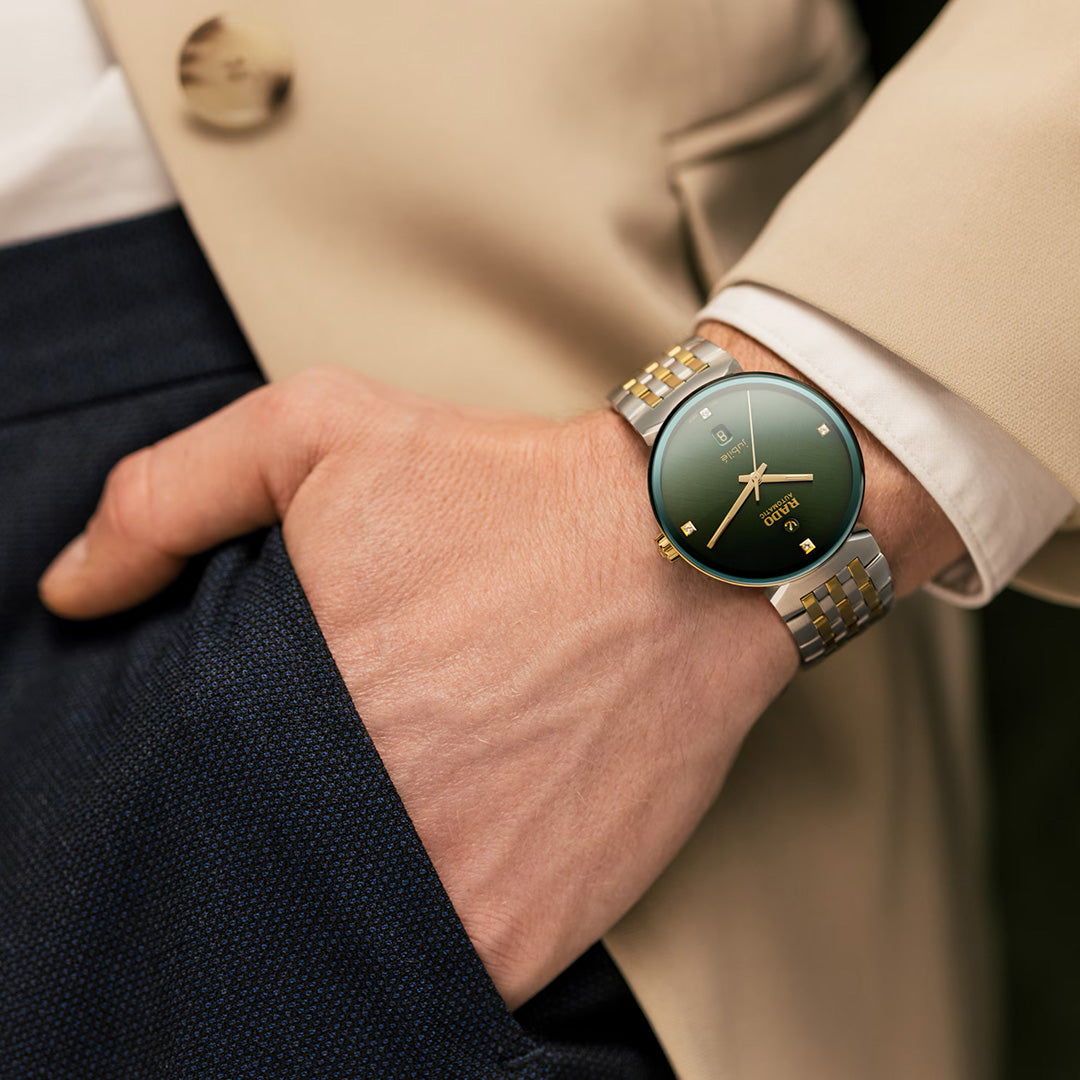A person in a beige blazer and navy pants has their hand in their pocket, wearing the RADO Florence Automatic 39mm Watch.