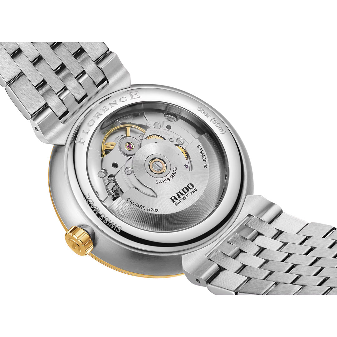 Close-up of the back of a RADO Florence Automatic 39mm Watch, highlighting the detailed mechanical movement visible through its transparent sapphire crystal caseback. The timepiece features a metal bracelet and a gold crown, with engraved details from RADO accenting the case edge.