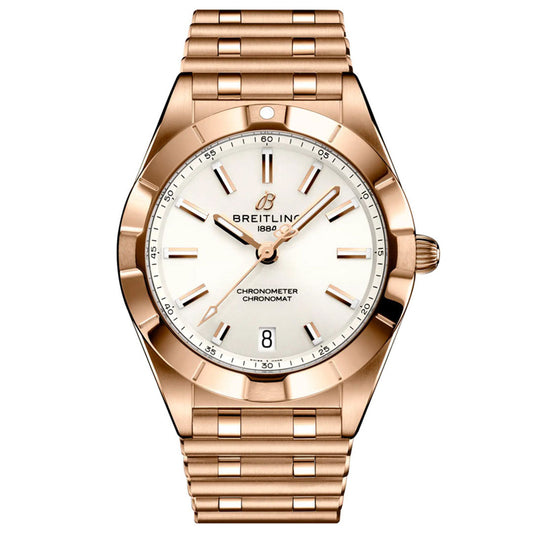 The BREITLING Chronomat 32 by Breitling features a gold case, white dial, gold hour markers, diamond-set bezel, date display at 6 o’clock, and a matching gold link bracelet.