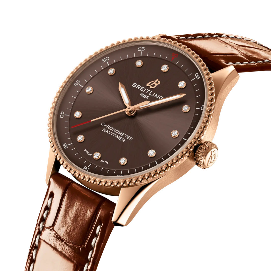 Introducing the BREITLING Navitimer 32 by Breitling—a luxurious pilot watch featuring a brown leather strap, a rose gold case, and a sophisticated brown dial embellished with diamond hour markers and gold hands. The dial is elegantly inscribed with "Chronometer Navitimer" and "Swiss Made," embodying the refined craftsmanship synonymous with luxury timepieces.
