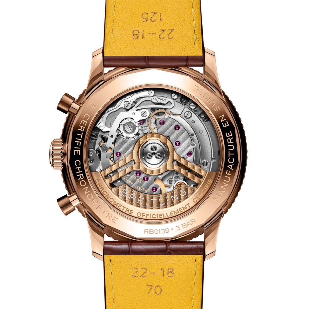Close-up of the BREITLING Navitimer B01 Chronograph 41’s transparent caseback, showcasing its finely crafted mechanical gears and components within a gold casing and yellow leather strap. Detailed engravings and markings encircle the edge and adorn the strap, emphasizing its heritage as an iconic aviation timepiece by Breitling.