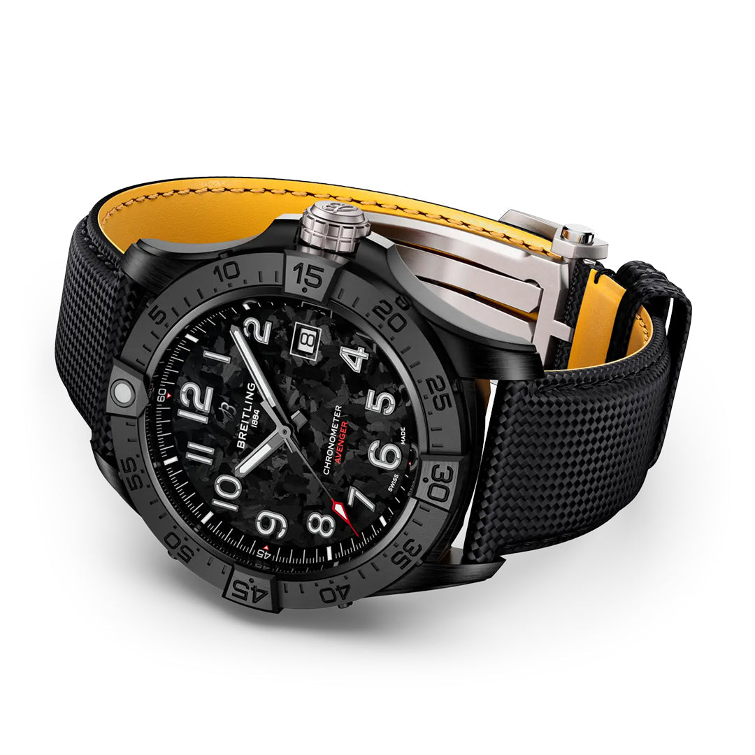 The BREITLING Avenger Automatic 42 Night Mission features a textured carbon fiber dial with luminescent white numbers and hands in an aviation style, a date display at 3 o'clock, a yellow inner band, and a textured black strap with a military leather buckle clasp.