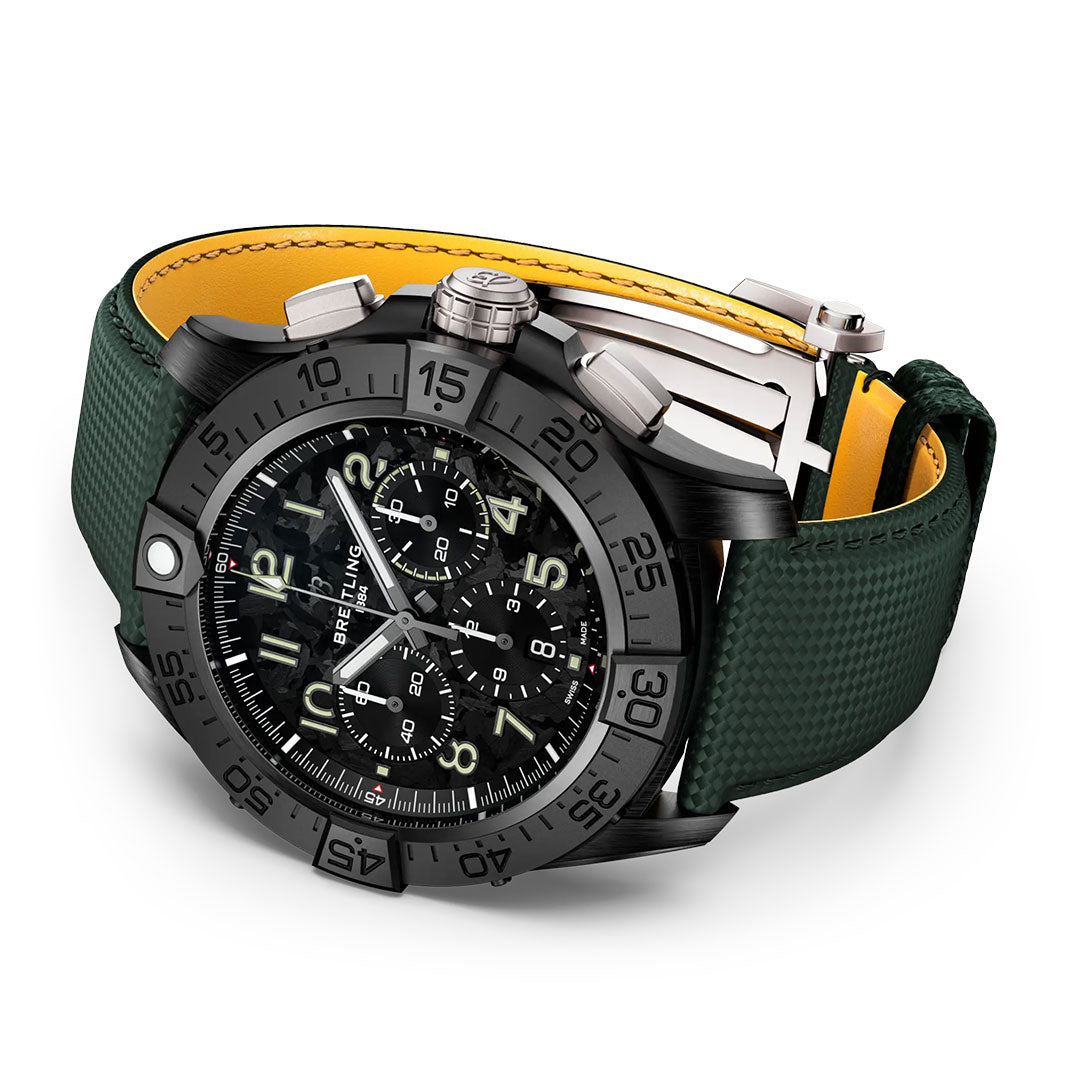 The BREITLING Avenger B01 Chronograph 46 Night Mission is a black Breitling watch with a detailed black face, multiple subdials, black bezel, and a dark green textured strap with yellow lining.